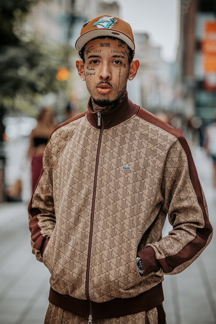 Stylish man with tattoos poses in a fashionable tracksuit in Montreal's urban setting.