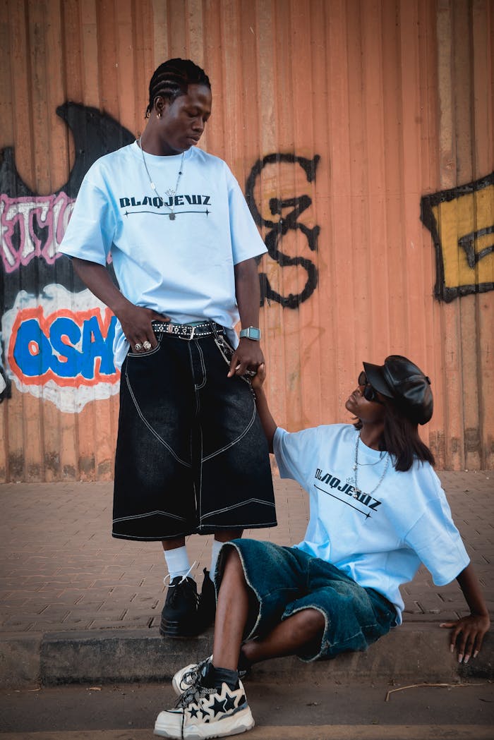Home Two adults in trendy streetwear pose by a graffiti wall, exuding urban style.